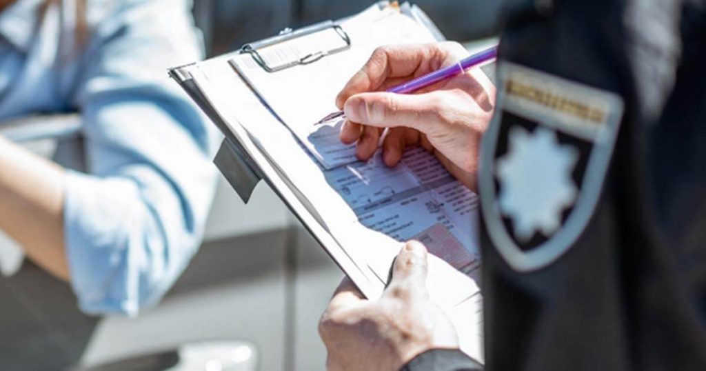 officer writing a ticket to a young woman for speeding on a sunny day