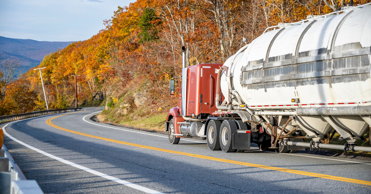 semi driving down a hill with forests on the side