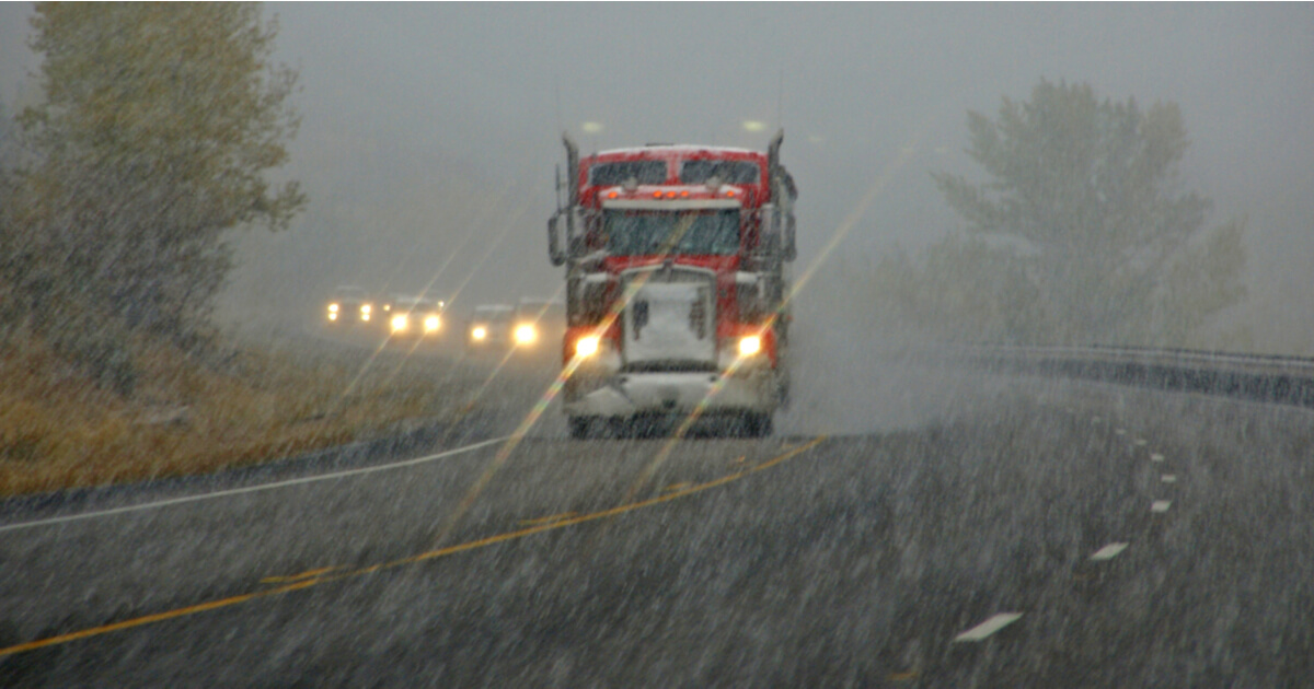 Semi truck and other vehicles driving on a highway through a rain storm