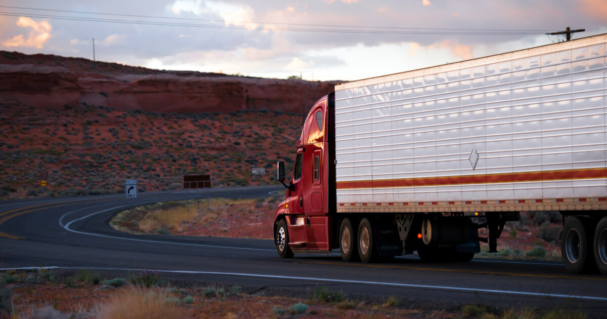 red semi truck driving on arizona desert highway at dusk