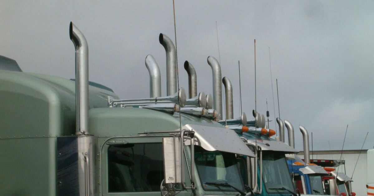 Semi trucks parked at at truck stop, focused on their exhausts