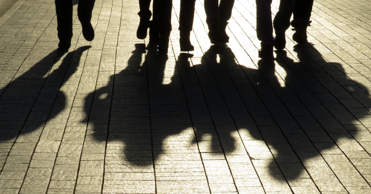 shadow od men walking down a dark alley