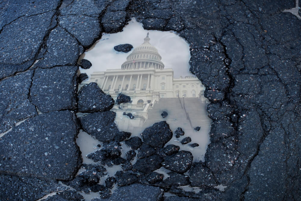 cracked road with puddle and capital building