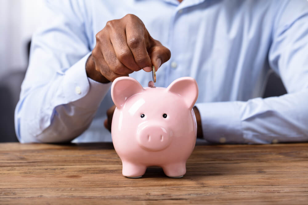 Man putting coins into biggy bank