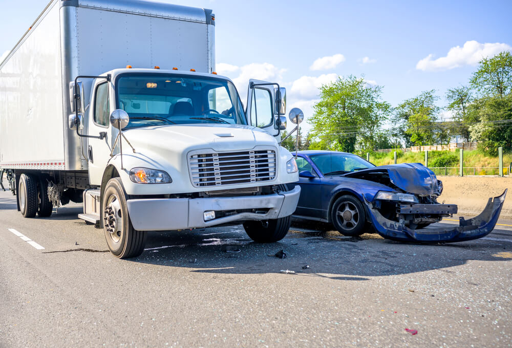 Box truck and car on side of road after collision