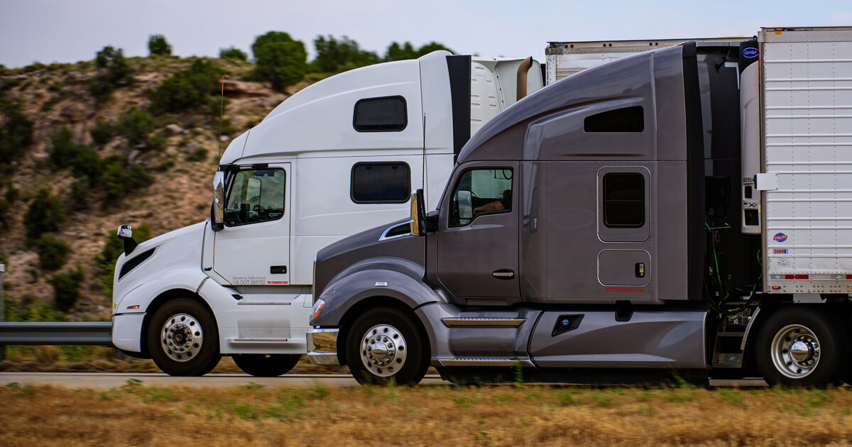 one white and one grey semi truck on a highway in arizona